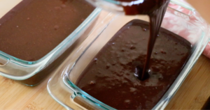 pouring the chocolate banana cake batter into pans