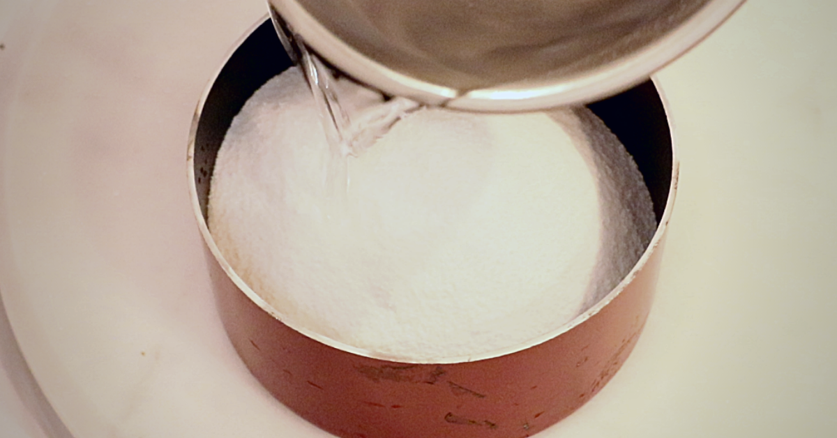 adding water in sugar in a pan