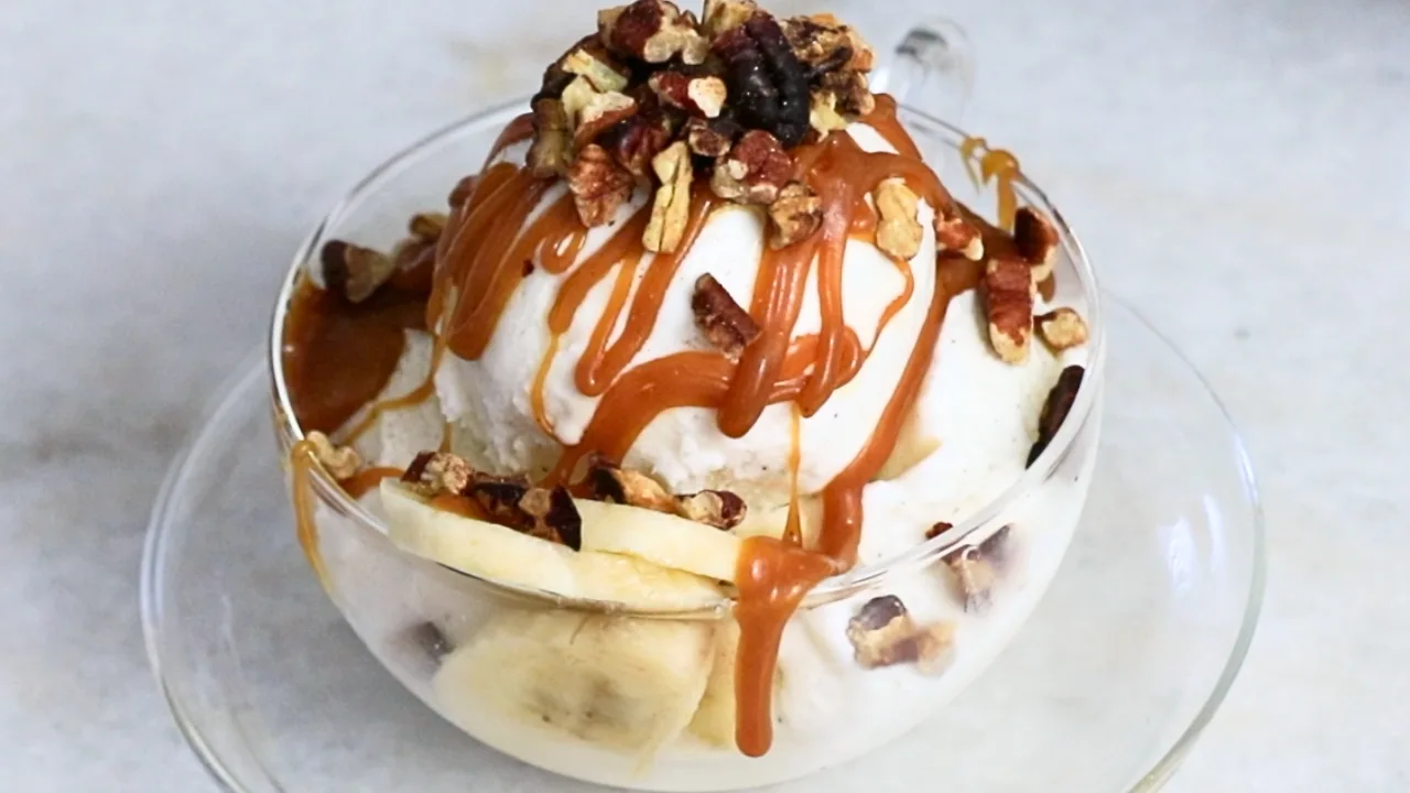 homemade caramel sauce and pecans on ice cream in a glass cup