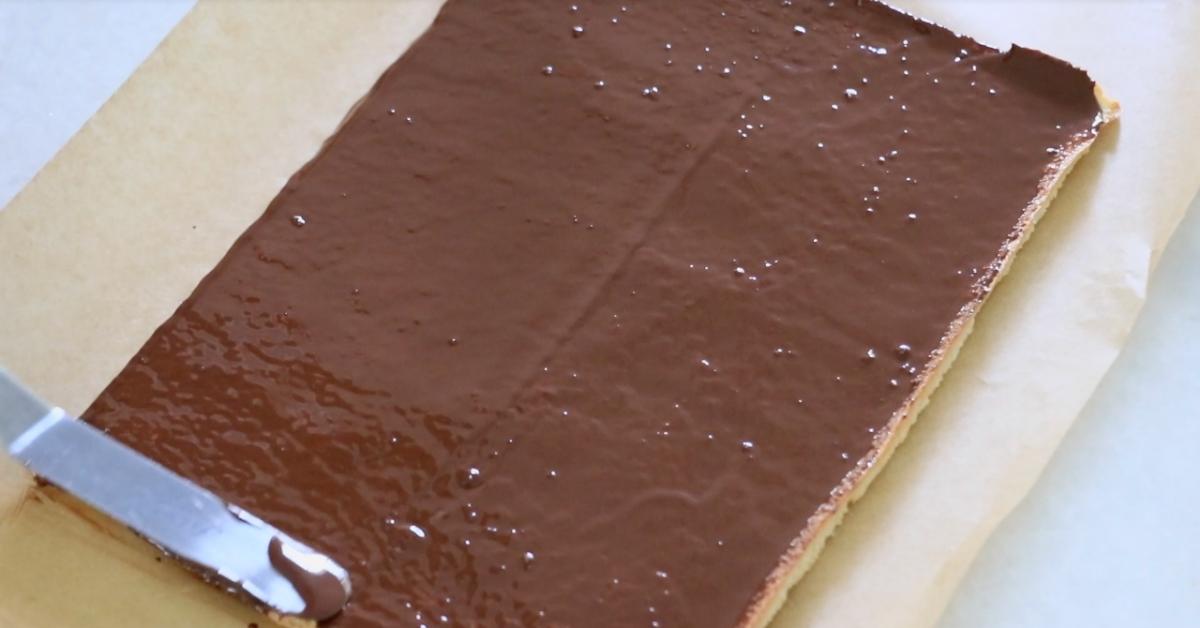 spreading a thin layer of chocolate on a biscuit joconde sponge