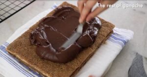 spreading dark chocolate ganache on biscuit sponge to build a opera cake