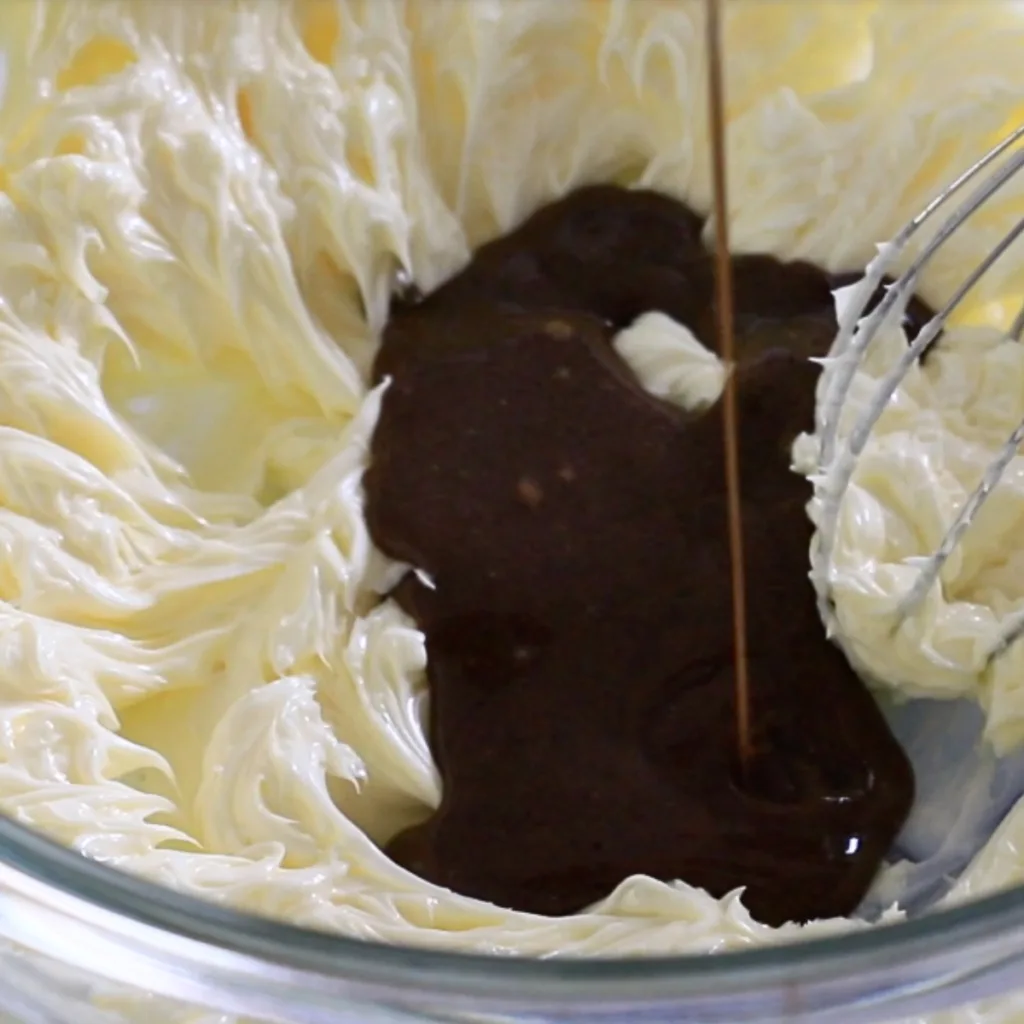adding coffee anglaise sauce to whipped butter to make coffee buttercream