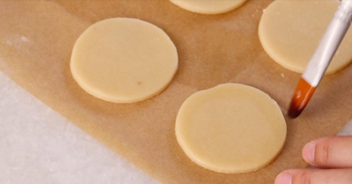 applying egg wash on circle cookie dough