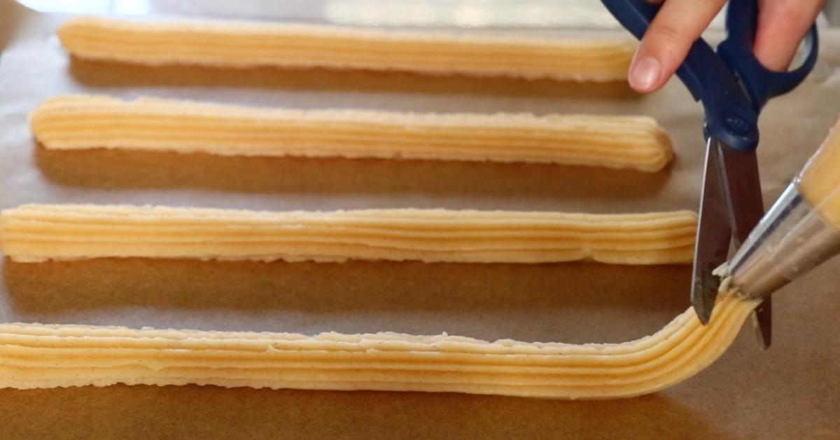 piping churros on a parchment paper