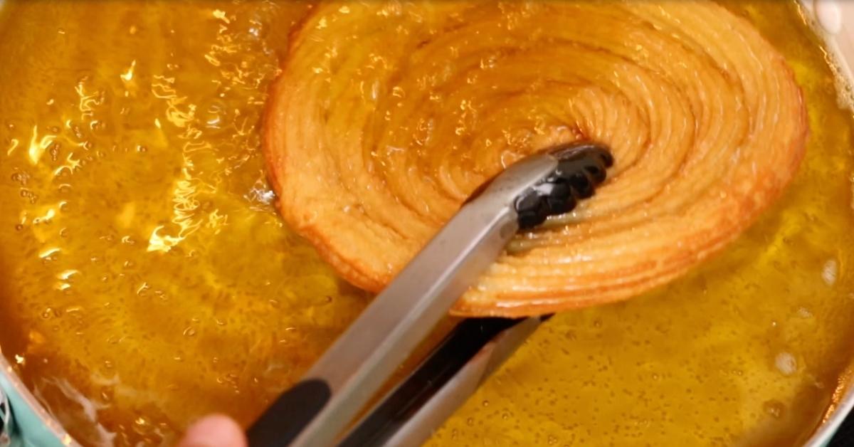 taking out a swirled shape churros from oil
