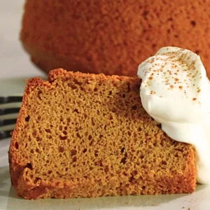a slice of pumpkin pie spice chiffon cake with whipped cream on a plate