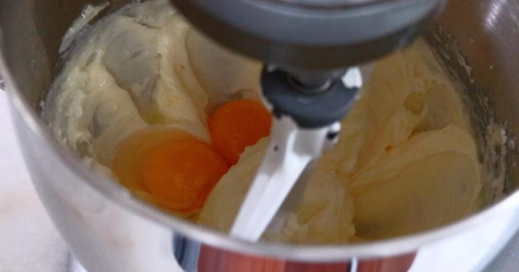adding eggs in a mixing bowl to make cookie dough