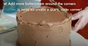 adding more buttercream on corner edges of the whole cake to frost a cake