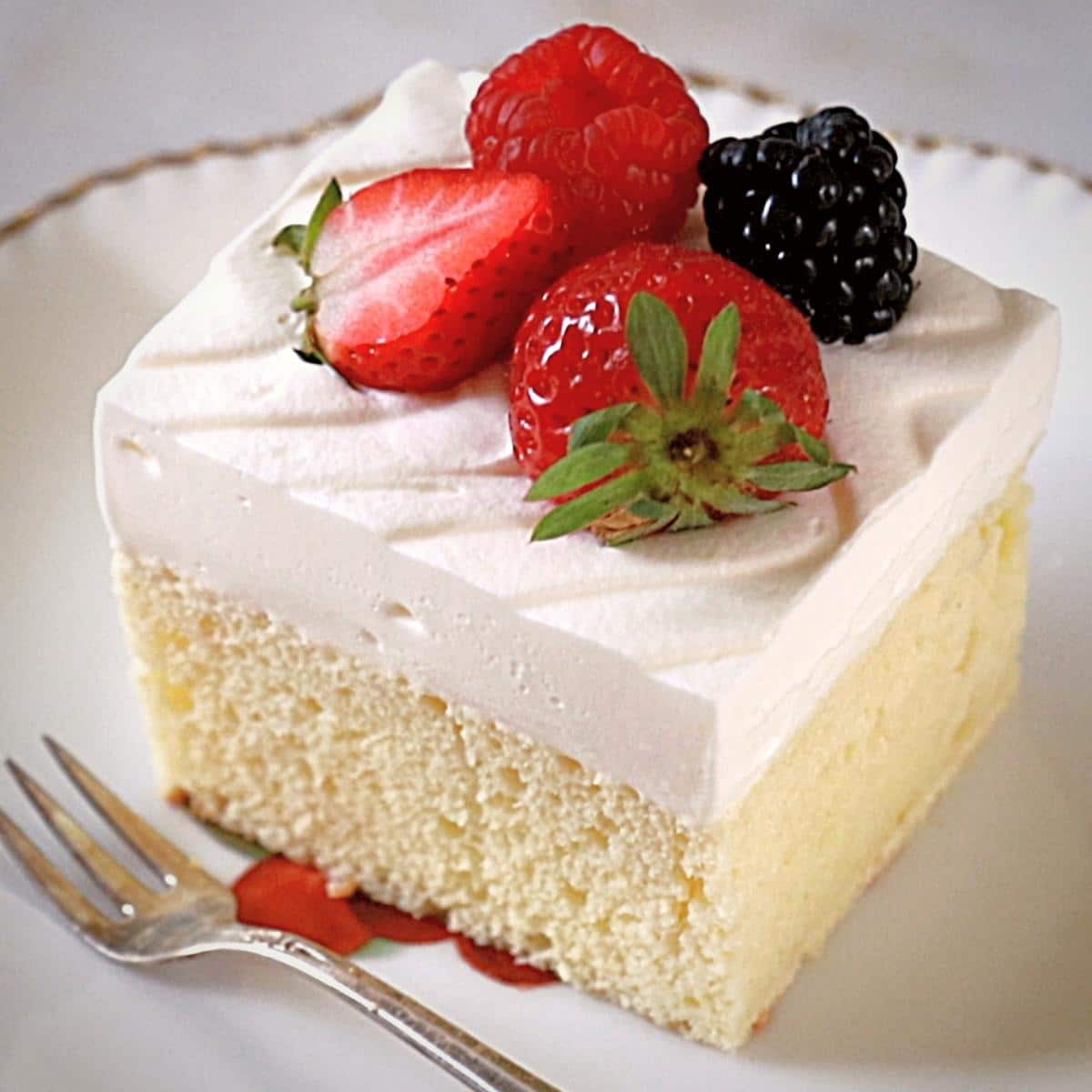 a tres leches cake on an antique plate with a fork