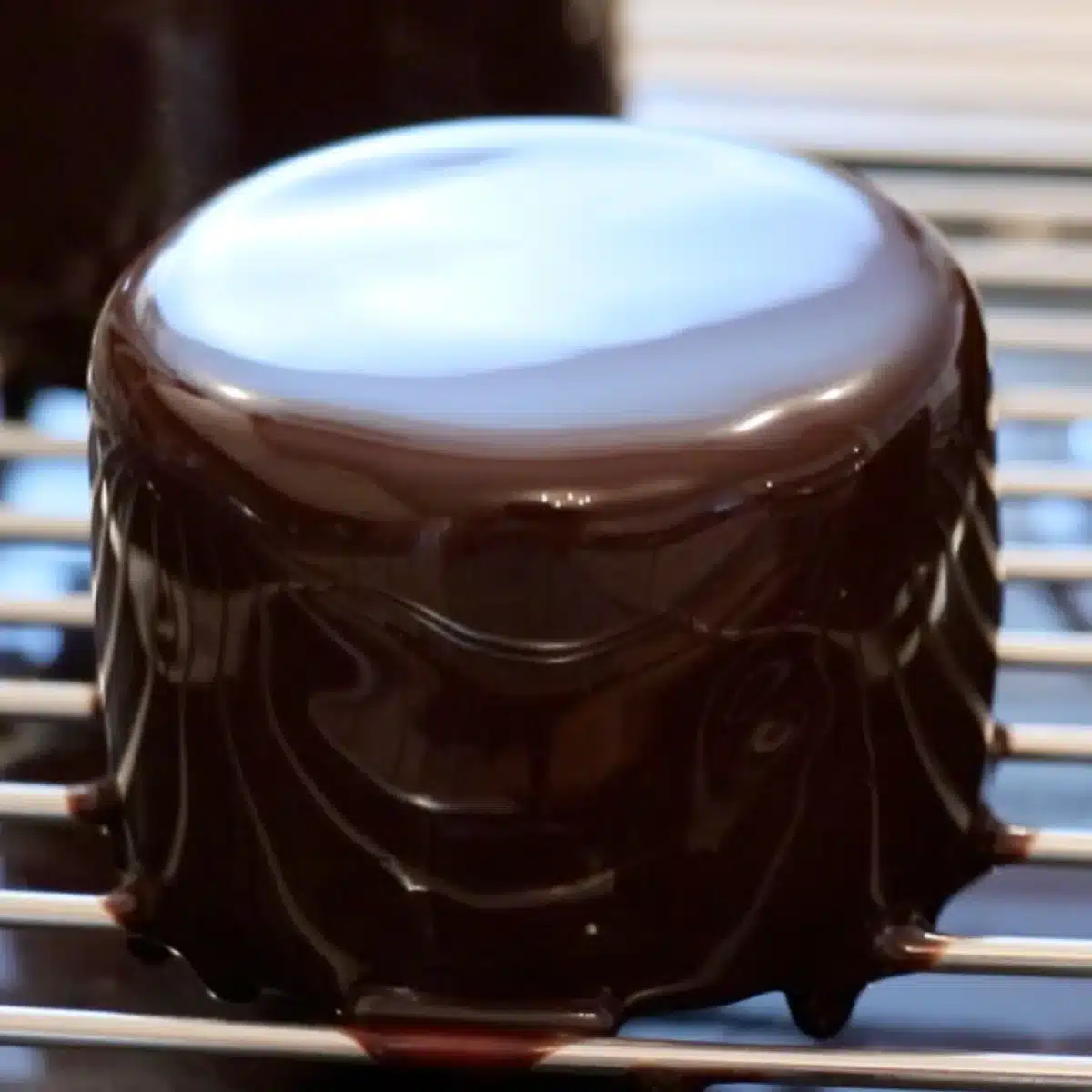 shiny chocolate mirror glaze cake on a rack