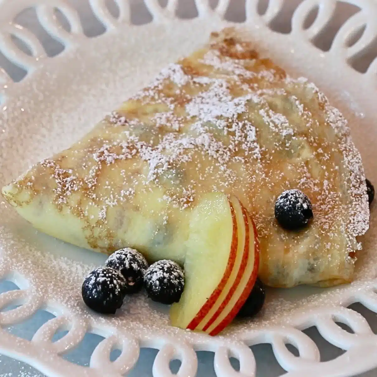 crepe filled with whipped cream, yogurt, blueberries, and peach