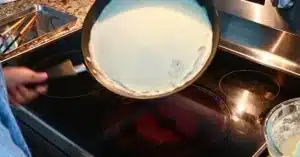 spreading crepe batter all over the hot pan