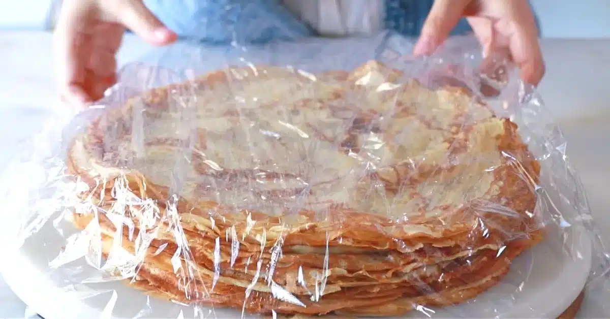 covering layers of crepes with plastic wrap