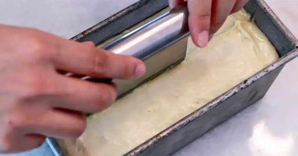 inserting melted butter with a dough scraper to bake lemon pound cake