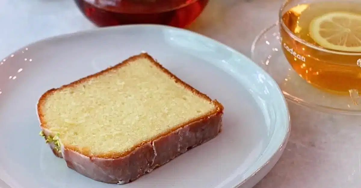 a slice of lemon pound cake on a plate with a cup of lemon tea
