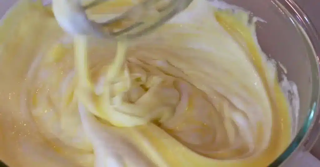 folding meringue in yolk mixture to make fluffy strawberry cream cake