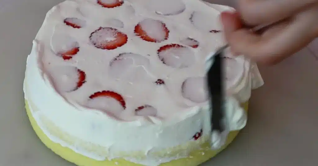 frosting whipped cream on sponge to make strawberry cream cake