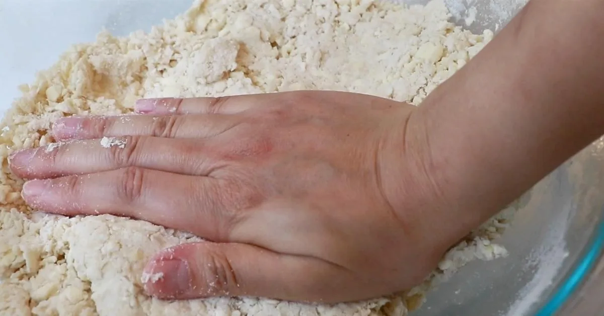 pushing pie dough with a hand