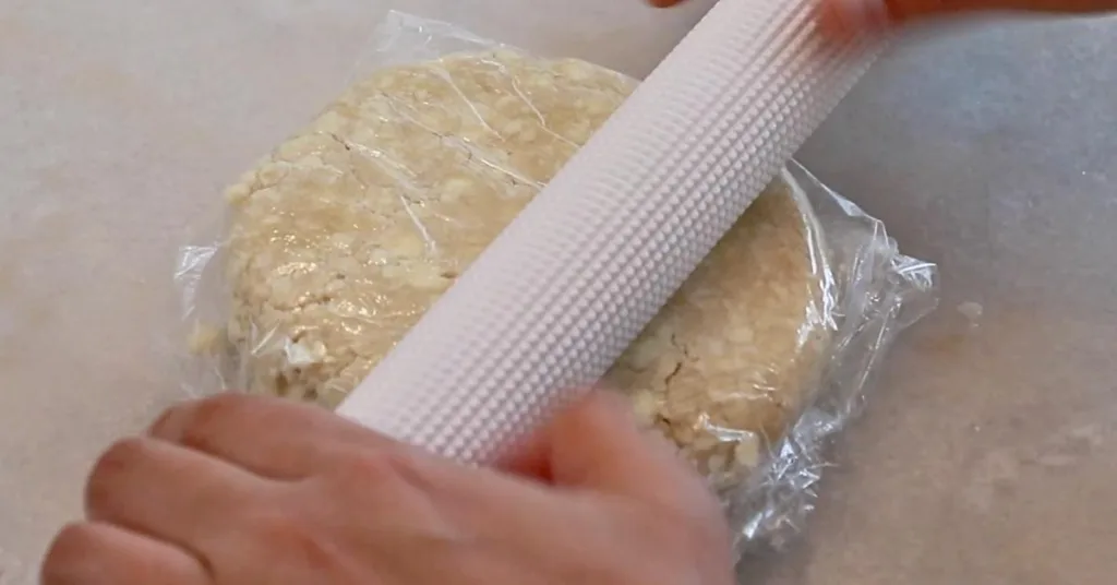 rolling pie dough wrapped in plastic wrap