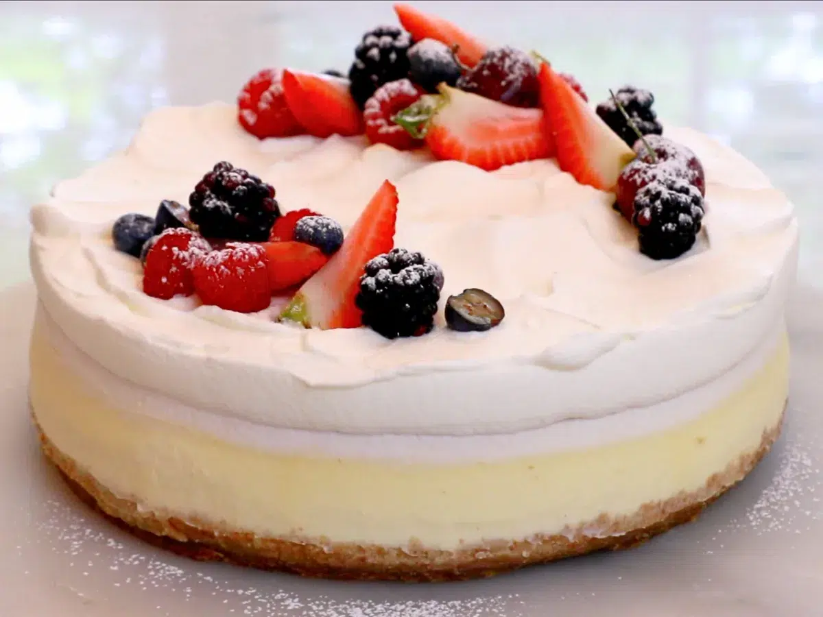 a whole baked cheesecake with whipped cream and fruits on top