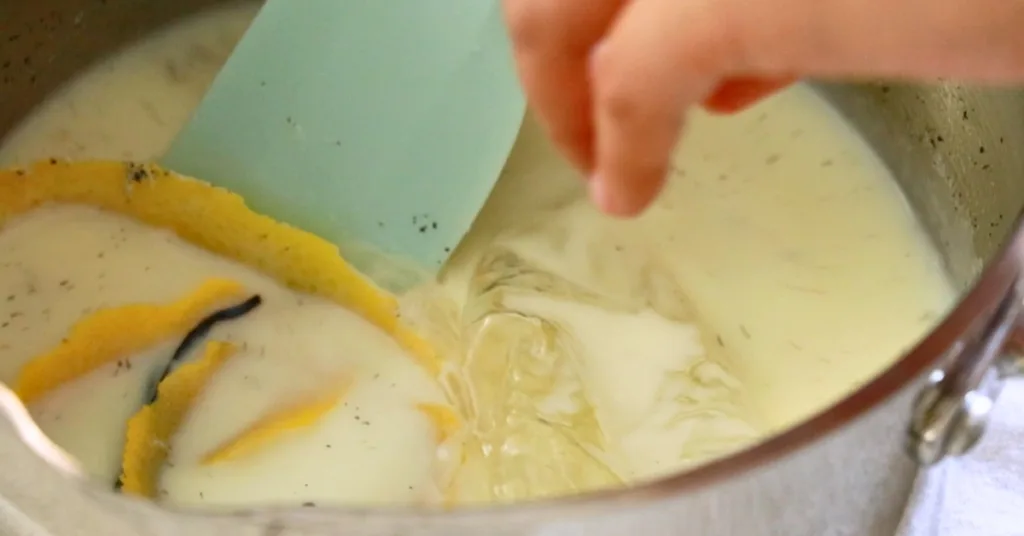 adding gelatin to sugar, milk, lemon peel, and vanilla beans in a pot