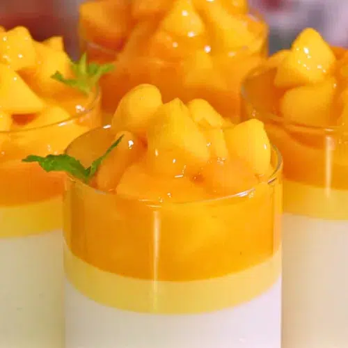 layers of vanilla and mango panna cotta with melty mango topping in glasses