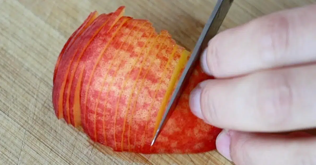 slicing fresh peach to make peach tart