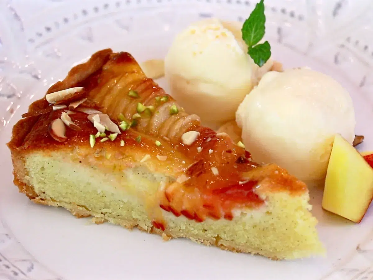 a slice of peach tart with scoops of ice cream and mint on a plate
