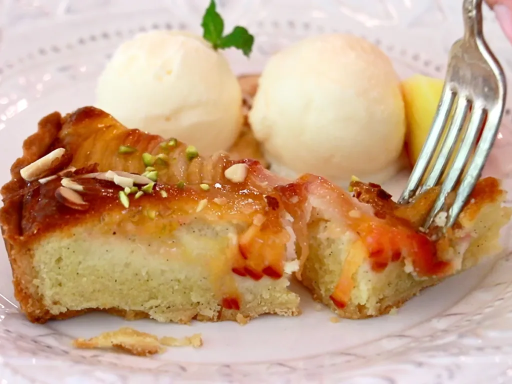 eating a slice of peach tart with scoops of ice cream on a plate