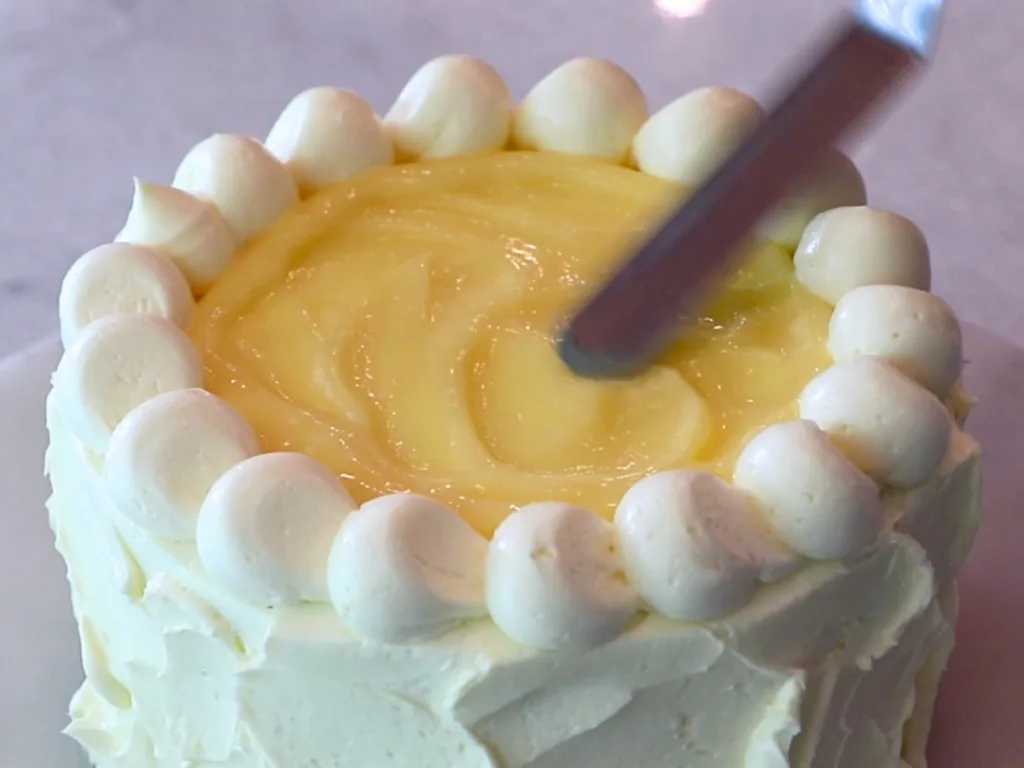 spreading lemon curd on top of a cake