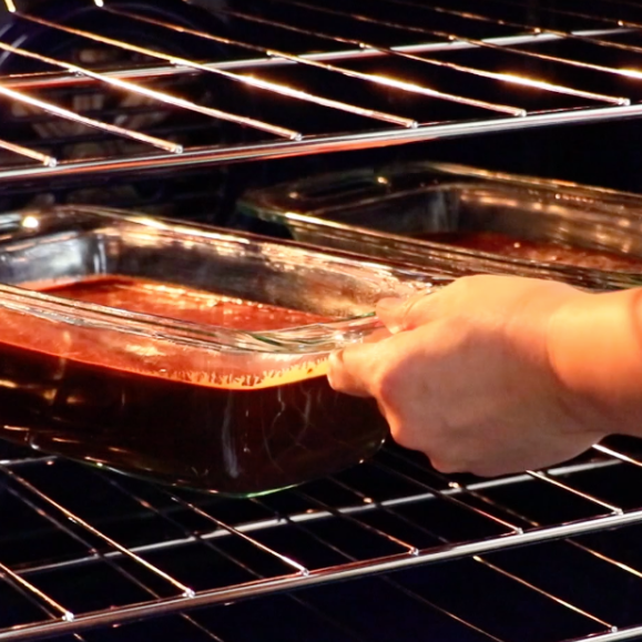 placing 2 pans filled with chocolate banana cake batter in the oven