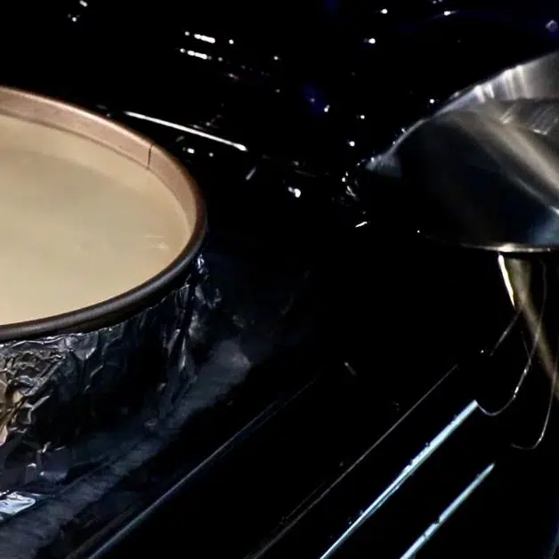 pouring hot water into tray with a cheesecake pan
