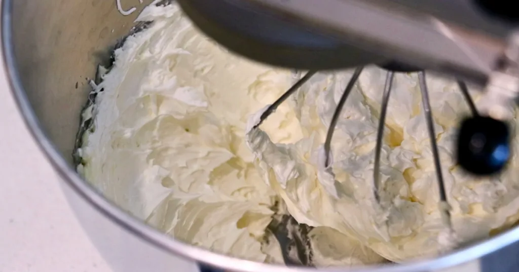 mixing butter and Swiss meringue to make Swiss buttercream