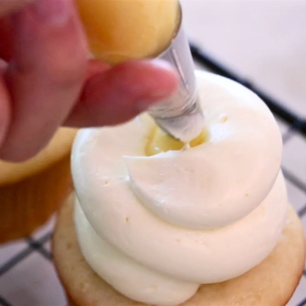 piping lemon curd in the middle of cupcakes