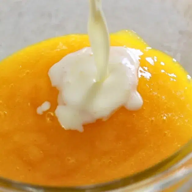 adding vanilla panna cotta base to pureed mango