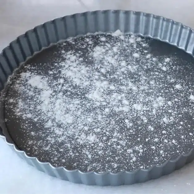 dusting bread flour on a tart pan
