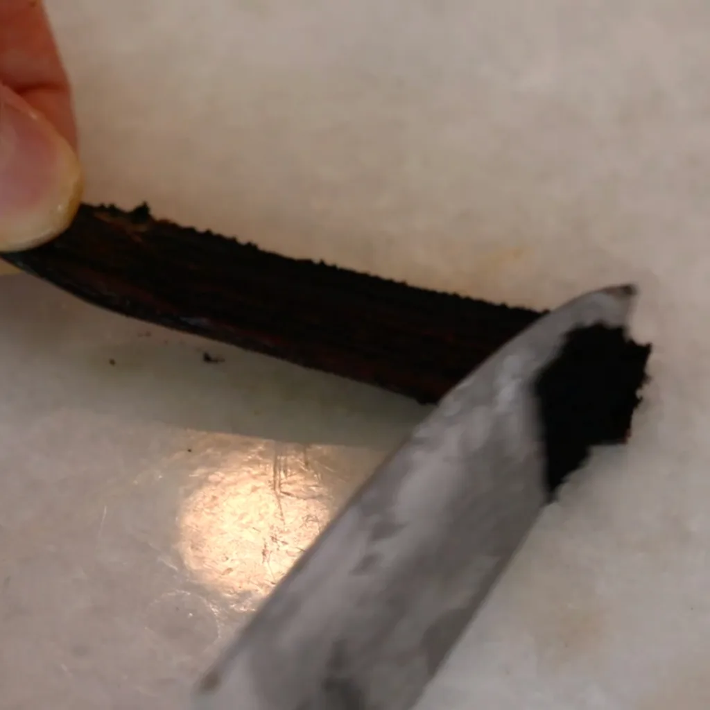 scraping off vanilla beans in a pod