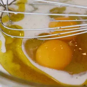 adding egg, milk, oil, and, honey in a bowl