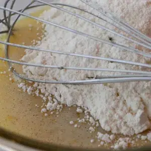 adding flour in madeleine batter