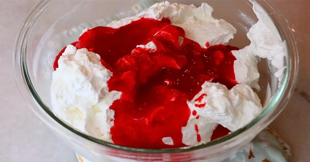 pouring raspberry puree into heavy cream and meringue