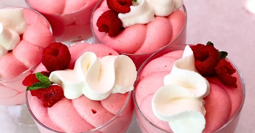 aspberry mousse in glass cups with whipped cream and fresh raspberries