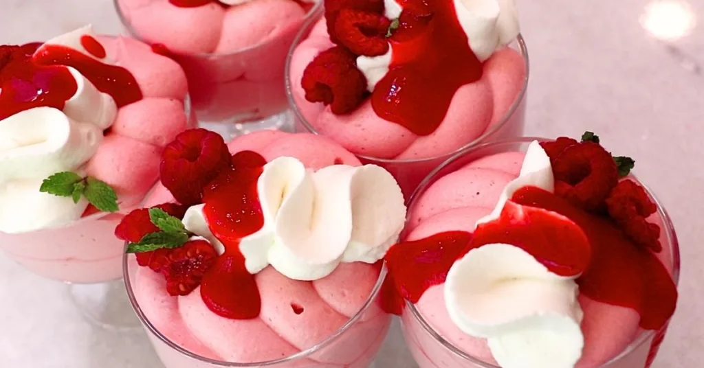 homemade raspberry mousse in cups with whipped cream, fresh raspberries, and raspberry sauce