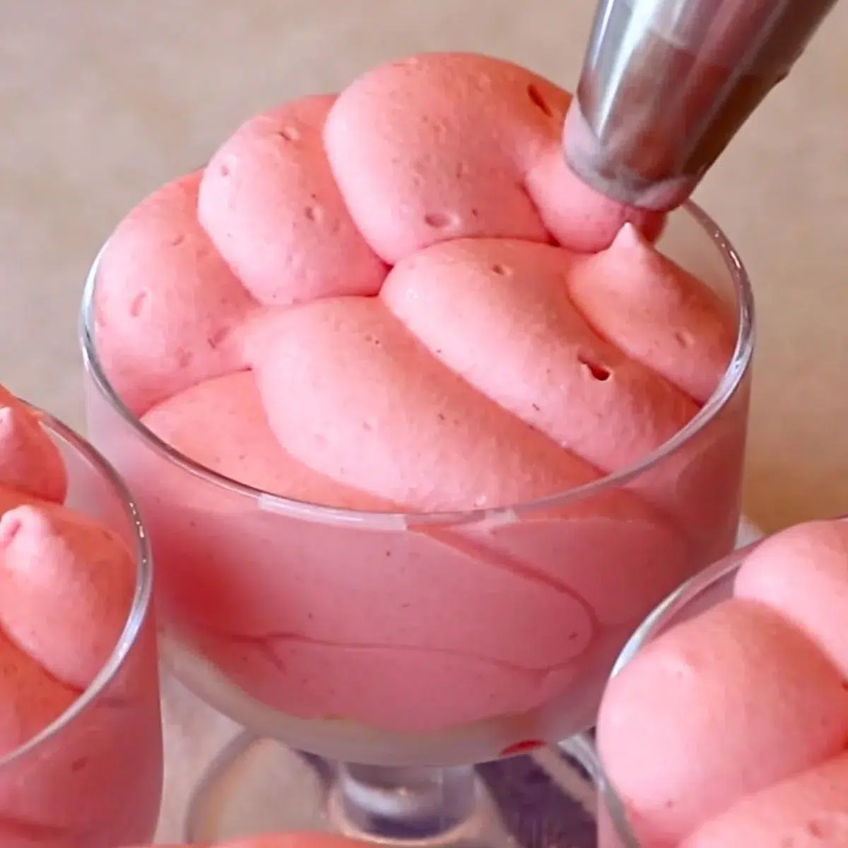 piping raspberry mousse in glass cups