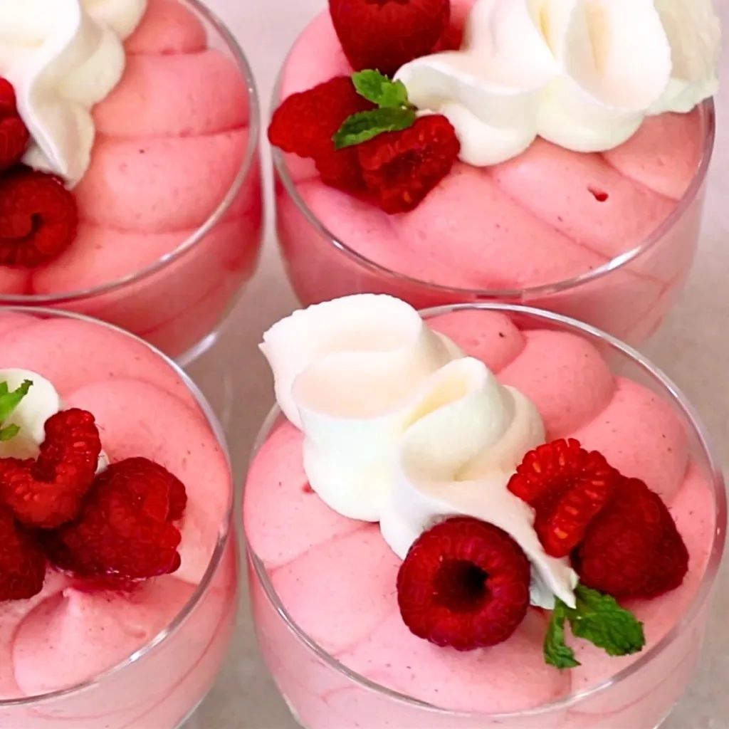 fluffy raspberry mousse in cups with whipped cream and fresh raspberries