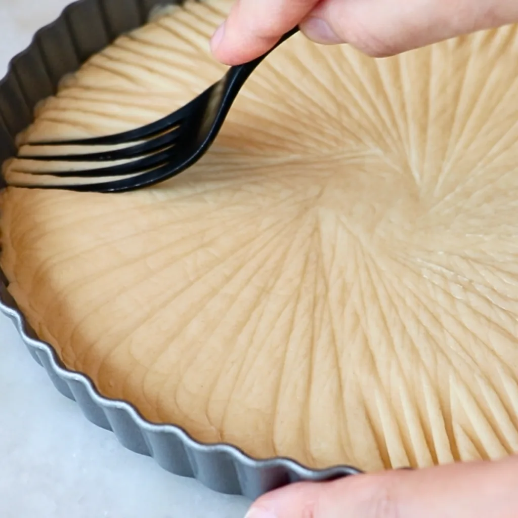 adding patterns with a fork to the edge of pressed shortbread cookies