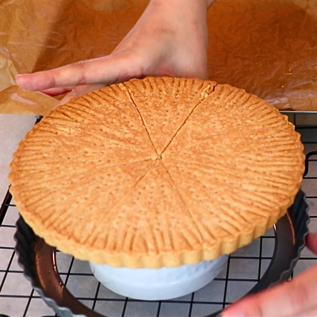 removing a tart pan from baked pressed shortbread cookies