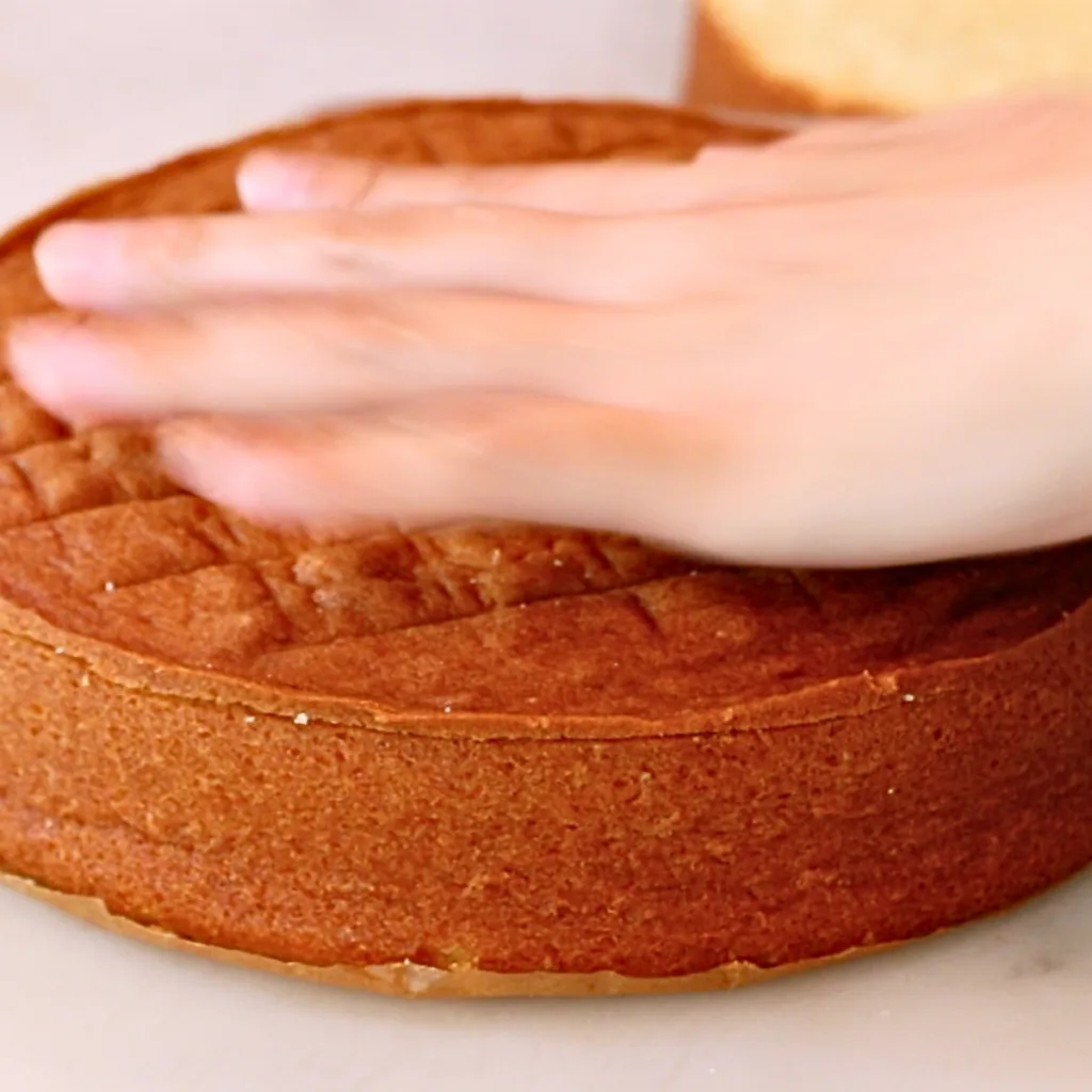 slicing off the surface of vanilla cake