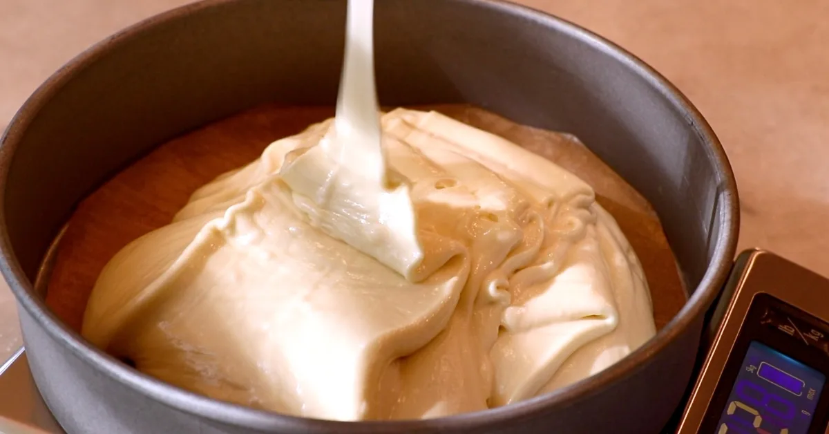 pouring vanilla cake batter into a pan
