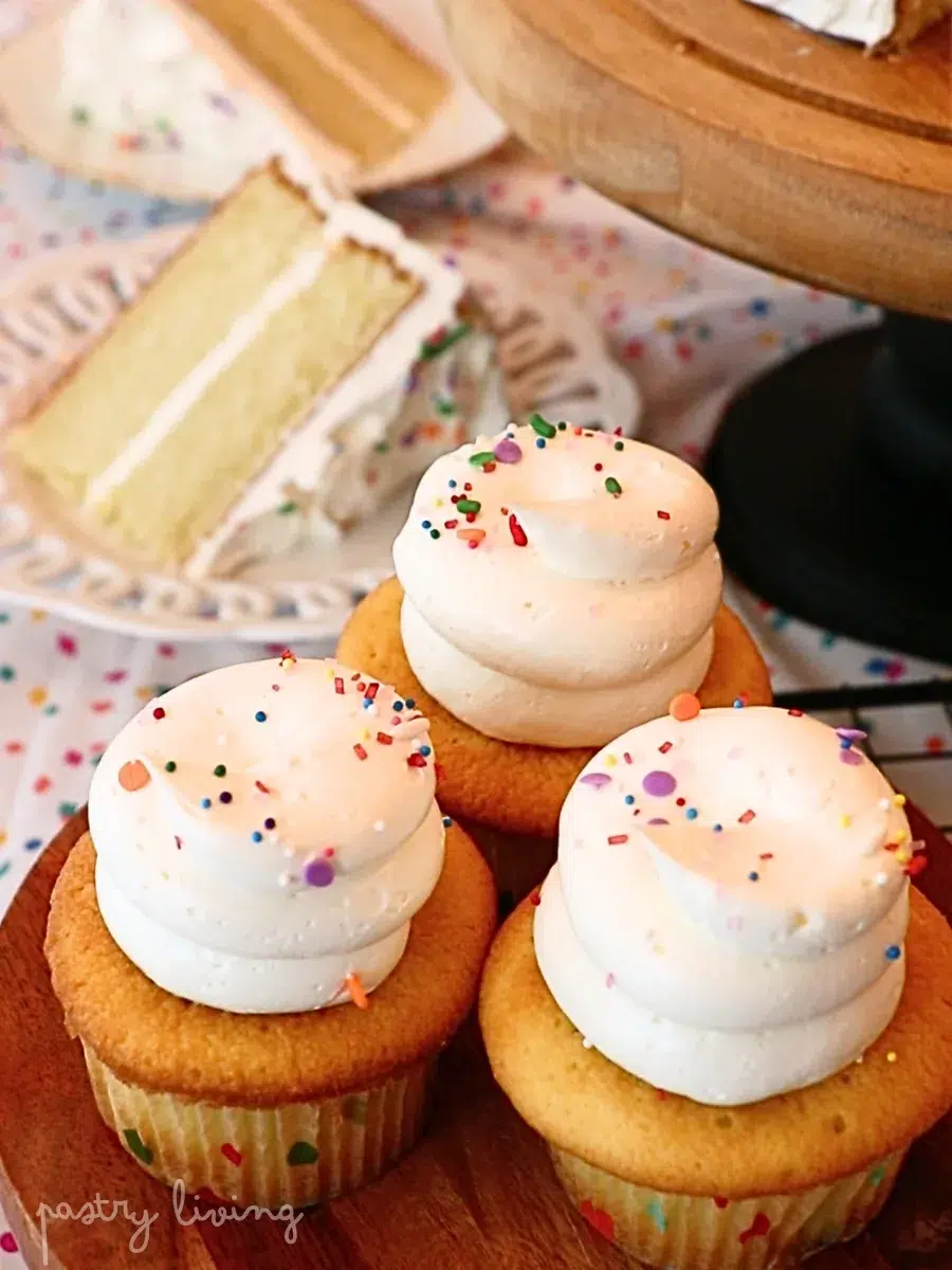 vanilla cupcakes and slices of vanilla cake frosted with buttercream