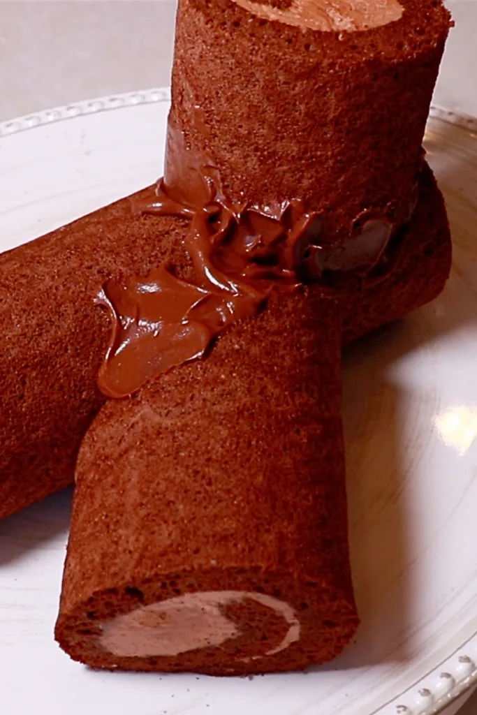 applying ganache on chocolate roll cake to make buche de noel